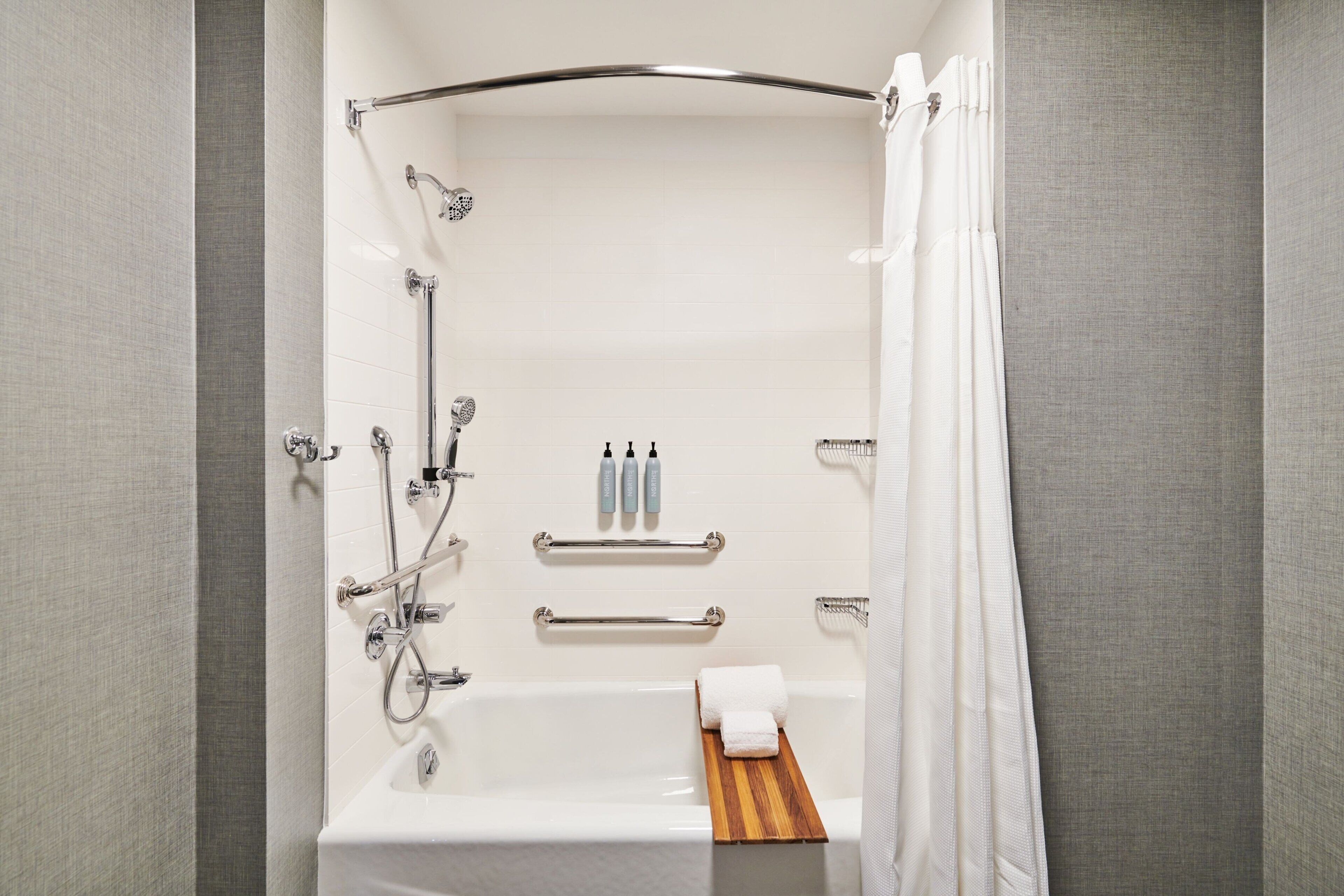 A modern bathroom with a bathtub, shower, and towel rack.