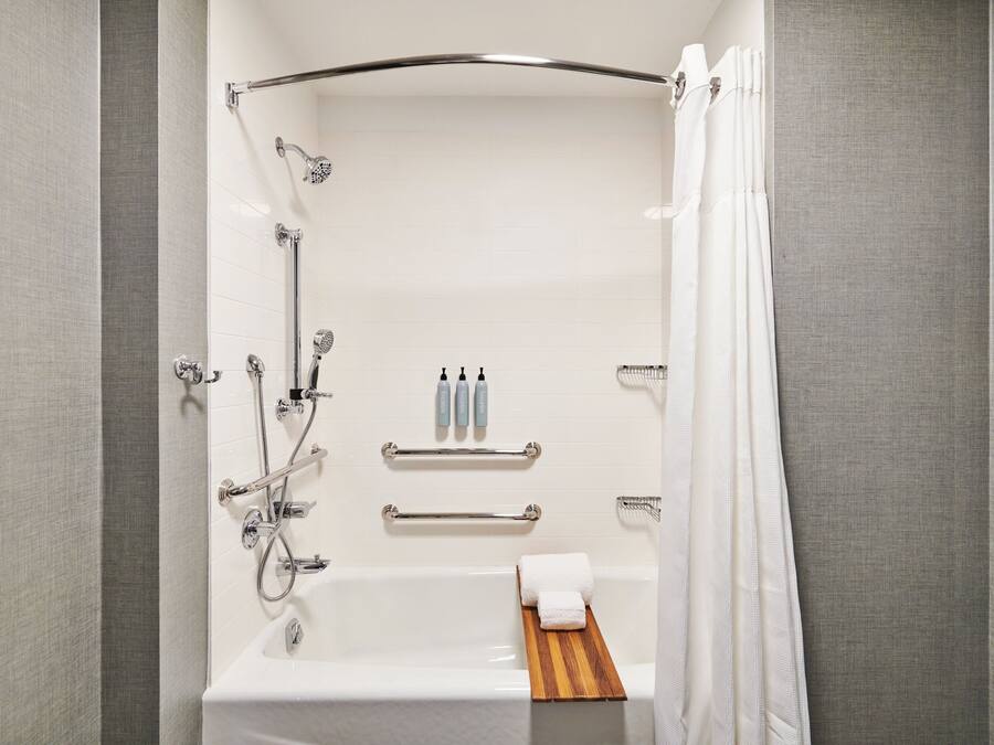 A modern bathroom with a bathtub, shower, and towel rack.