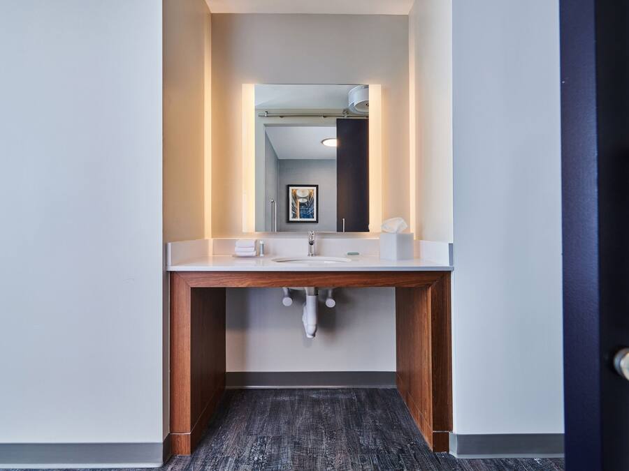 Un baño moderno con tocador de madera, lavamanos y espejo.