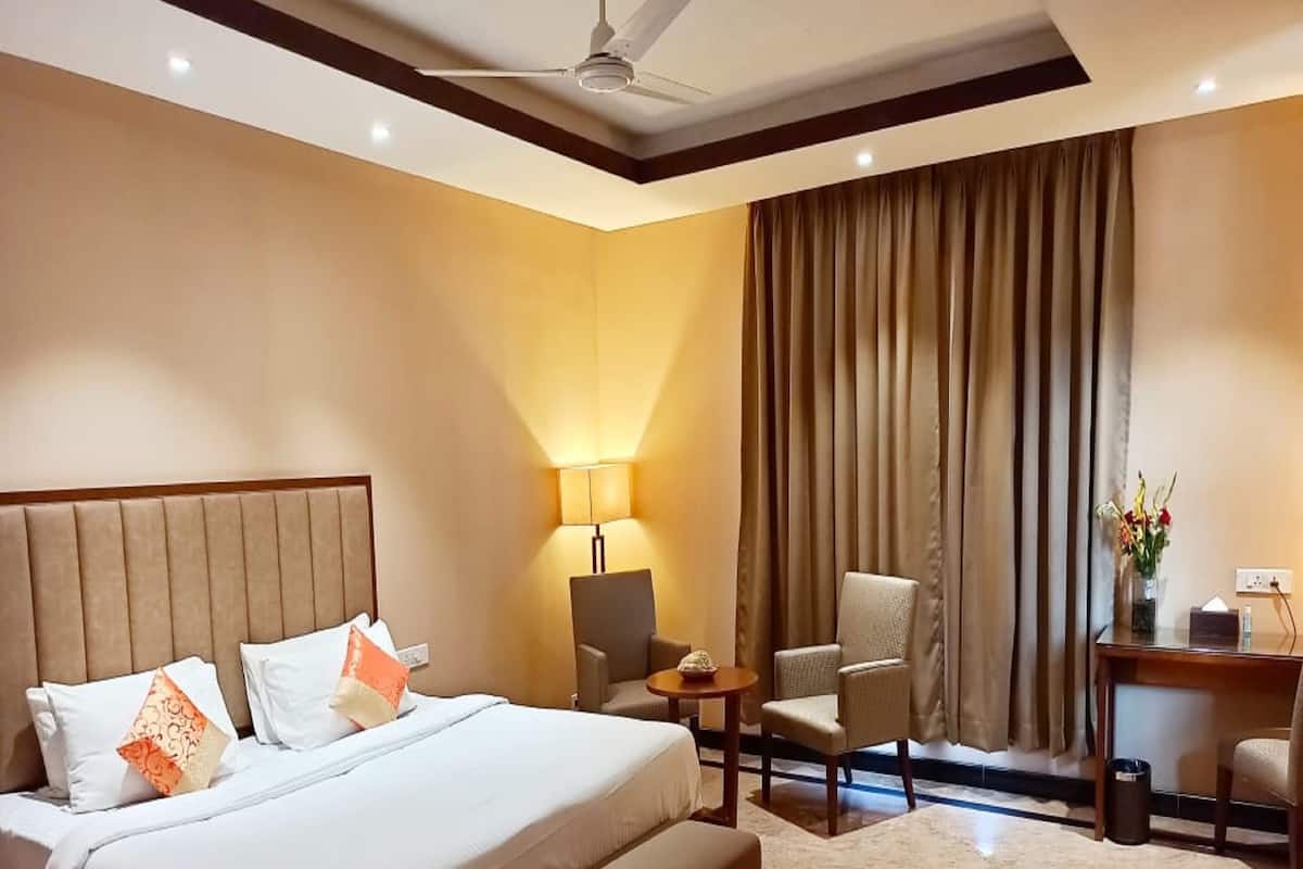 Una habitación de hotel con una cama grande, un escritorio, una silla y una lámpara.