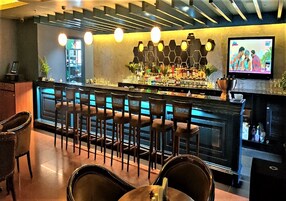 A bar area with a counter, stools, and a television screen.