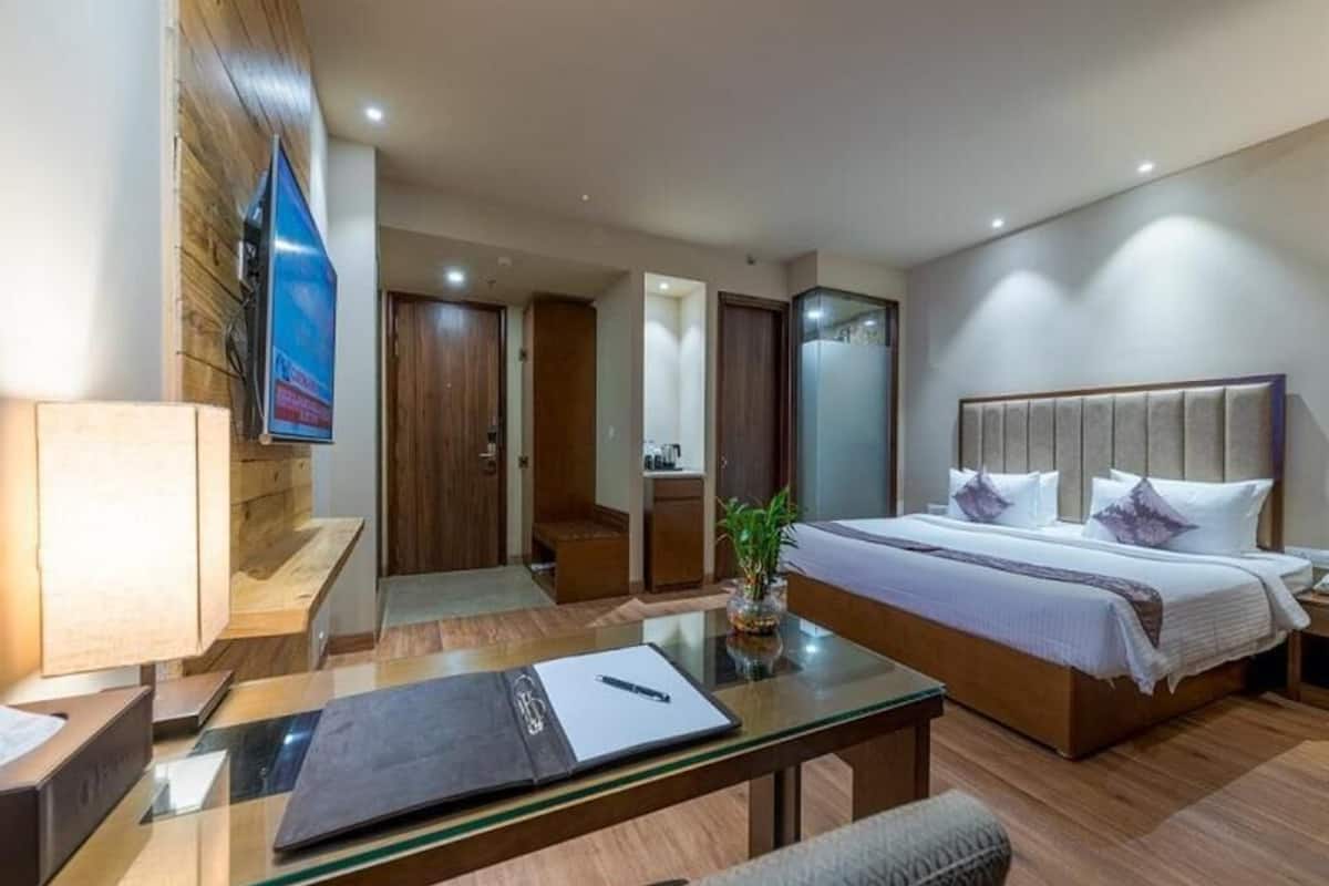 Una habitación de hotel con cama, mesita de noche, lámpara y escritorio con silla.