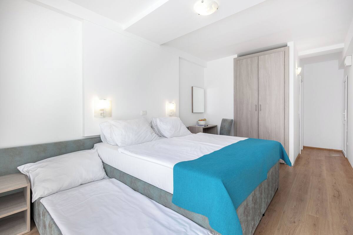 A bedroom with a bed, bedside tables, a wardrobe, and a door.