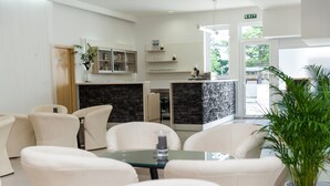 A modern hotel lobby with a seating area, a reception desk, and a stone accent wall. - Annex Slaven (Crikvenica)