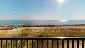 Une vue sur la plage avec une terrasse en bois et une clôture.