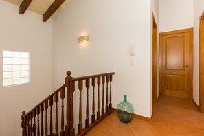 A staircase with wooden balusters, a wall-mounted light fixture, a telephone, and a door.