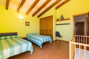A room with two beds, a wooden ceiling, a door, a chair, and a crib.