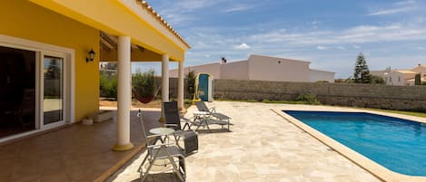 Un espace extérieur abrité, doté d’une piscine, d’un sol en pierre et de mobilier d’extérieur.
