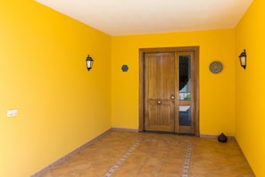 A hallway with yellow walls, a wooden door, and tiled flooring.