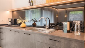 A modern kitchen with a built-in sink, a coffee maker, a toaster, and a vase with dried plants. - Apartment 'Lara Siela' with Mountain View, Private Terrace and Wi-Fi (St. Ulrich)