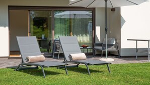 An outdoor seating area with two lounge chairs, a table, and an umbrella. - Apartment 'Lara Siela' with Mountain View, Private Terrace and Wi-Fi (St. Ulrich)