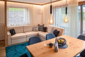 A modern living room with a wooden dining table, a beige sofa, and a blue chair.