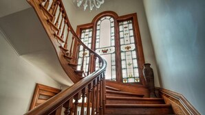 Una escalera de madera con diseño curvo que conduce a un espacio con amplios vitrales.