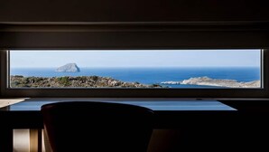 A room with a large window overlooking a rocky coastline and the sea. - Fiora Paradise Villa Resort (kythira)