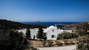 A white building with a dome, surrounded by greenery and overlooking a coastal landscape. - Fiora Paradise Villa Resort (kythira)