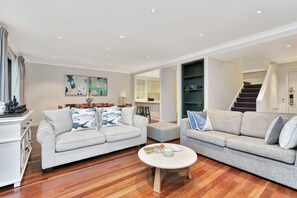 A modern living room with two grey sofas, a coffee table, and a dining area with a chessboard.