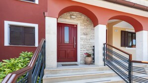 A red door with a stone wall, a staircase with metal railings, and a potted plant. - Apartments with Shared Pool Villa Rossella 1 (Rovinj)