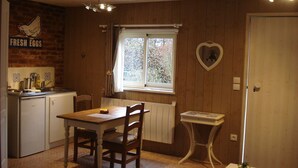 A compact kitchen with a dining table, chairs, a window, and a heart-shaped decoration on the wall. - Tara, guest studio in the countryside with kitchenette (Saint Sylvestre de Cormeilles)