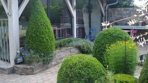 A conservatory with a glass roof, surrounded by well-maintained hedges and a brick pathway. - Tara, guest studio in the countryside with kitchenette (Saint Sylvestre de Cormeilles)