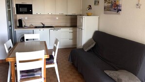 A compact living space with a kitchenette, a dining area with a table and chairs, and a sofa.