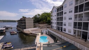Un hotel con zona de piscina, mobiliario exterior y vistas al agua.