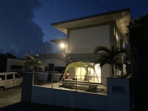 A modern building with a covered entrance and a white van parked outside. - JAM ClubHouse Resort (Yomitan)
