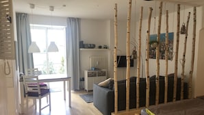 Un salon moderne avec un canapé, une table à manger et des chaises, ainsi qu’un téléviseur.