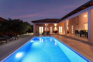 A swimming pool with lounge chairs and a covered patio area.