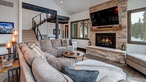 Una sala de estar moderna con una chimenea de piedra, un televisor de pantalla plana grande y un rincón de estar acogedor.