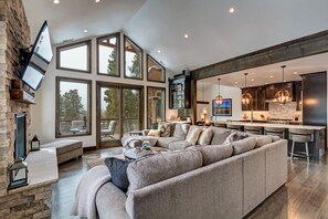 Relax in a spacious living area with a comfortable sofa and stone fireplace, offering views of the surrounding landscape.