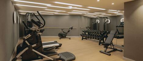 Un gimnasio moderno con máquinas de cardio, mancuernas y una bicicleta estática.