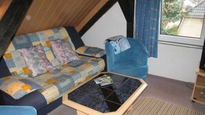 Une pièce chaleureuse avec un canapé matelassé, une petite table et une fenêtre avec des rideaux.