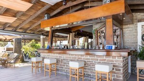 An outdoor bar area with a brick counter, wooden stools, and a rustic ceiling. - Villa Amorossa with Garden View & Shared Pool by Konnect, Roda Corfu (Corfu)