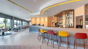 A modern bar area with a curved counter, multiple bar stools, and a seating area with tables and chairs. - Hampton by Hilton High Wycombe (High Wycombe)