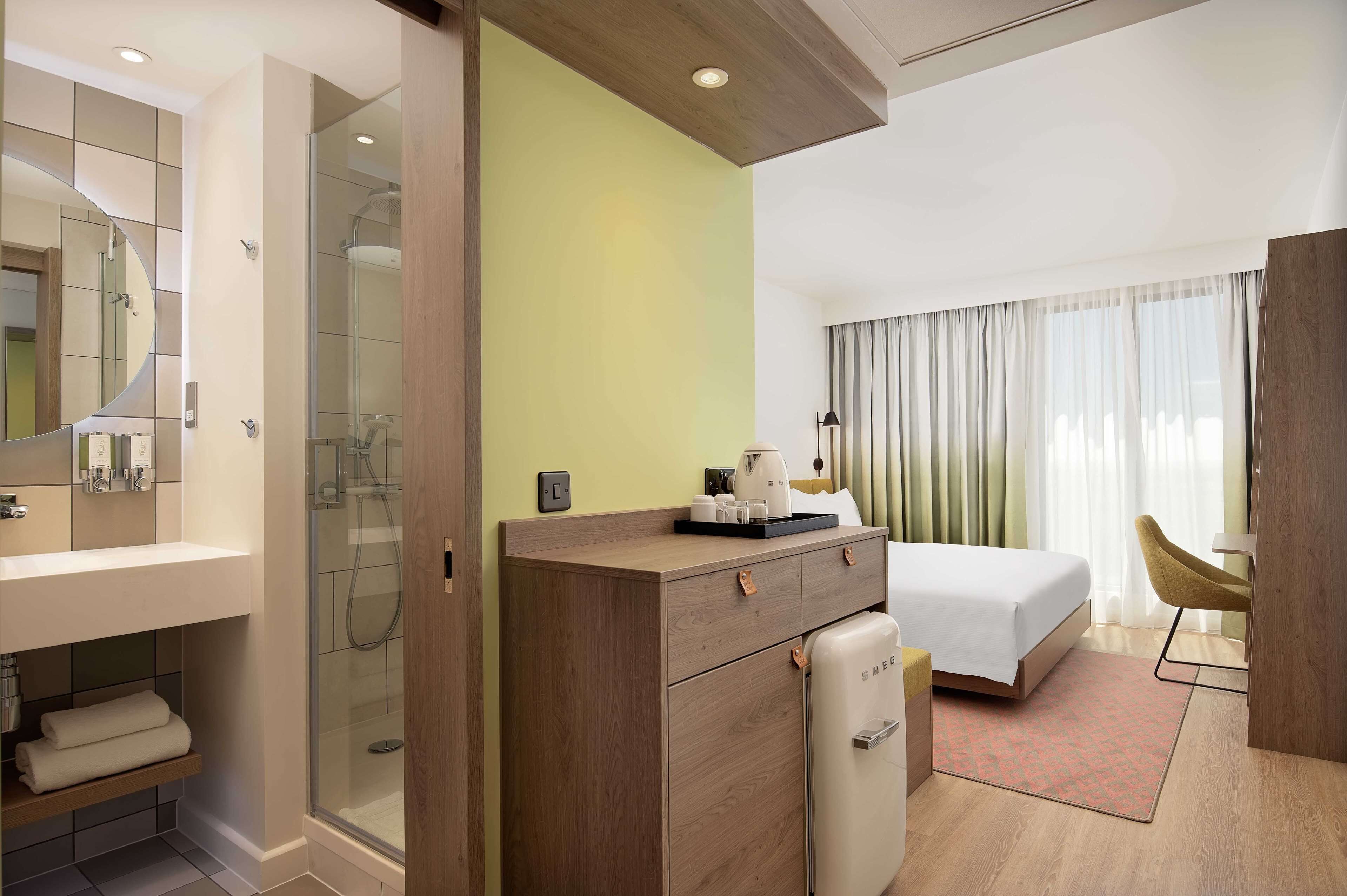 Una habitación de hotel con ducha, cama, escritorio y silla.