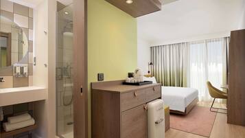 Una camera d'albergo con doccia, letto, scrivania e sedia.
