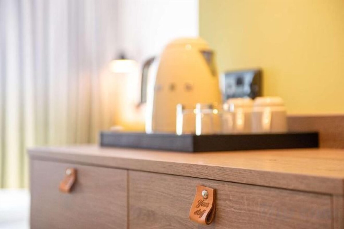 A wooden dresser with drawers and a tray holding a coffee maker and a small framed picture.