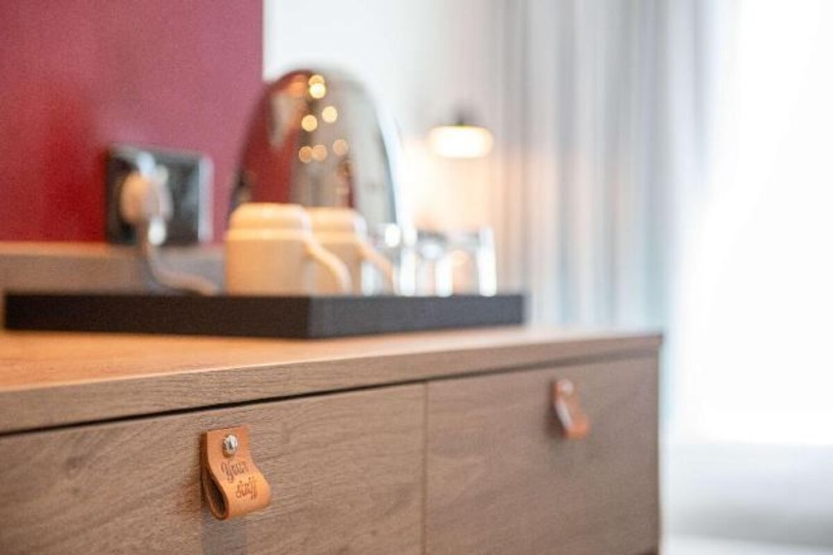 A wooden dresser with a drawer handle and a small leather tag.