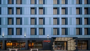 A modern hotel facade with a grid of windows and a prominent Hampton sign. - Hampton by Hilton High Wycombe (High Wycombe)