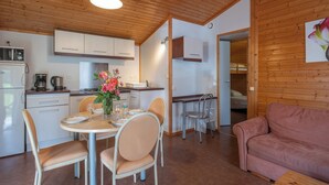 Uma cozinha moderna com armários brancos, uma mesa de jantar posta para quatro pessoas e um sofá rosa na sala de estar.