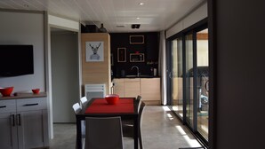 Una cocina moderna con comedor, que presenta un mantel rojo, sillas blancas y una paleta de colores blanco y negro.