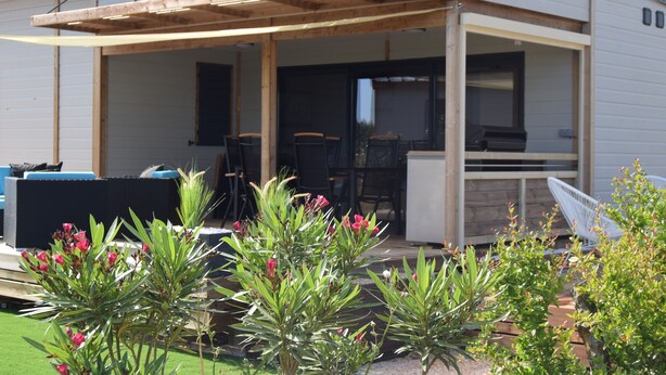 Un patio cubierto con mobiliario exterior, una parrilla y plantas en macetas.