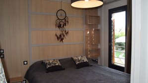 Un dormitorio con cama, un atrapasueños y una puerta a un balcón.