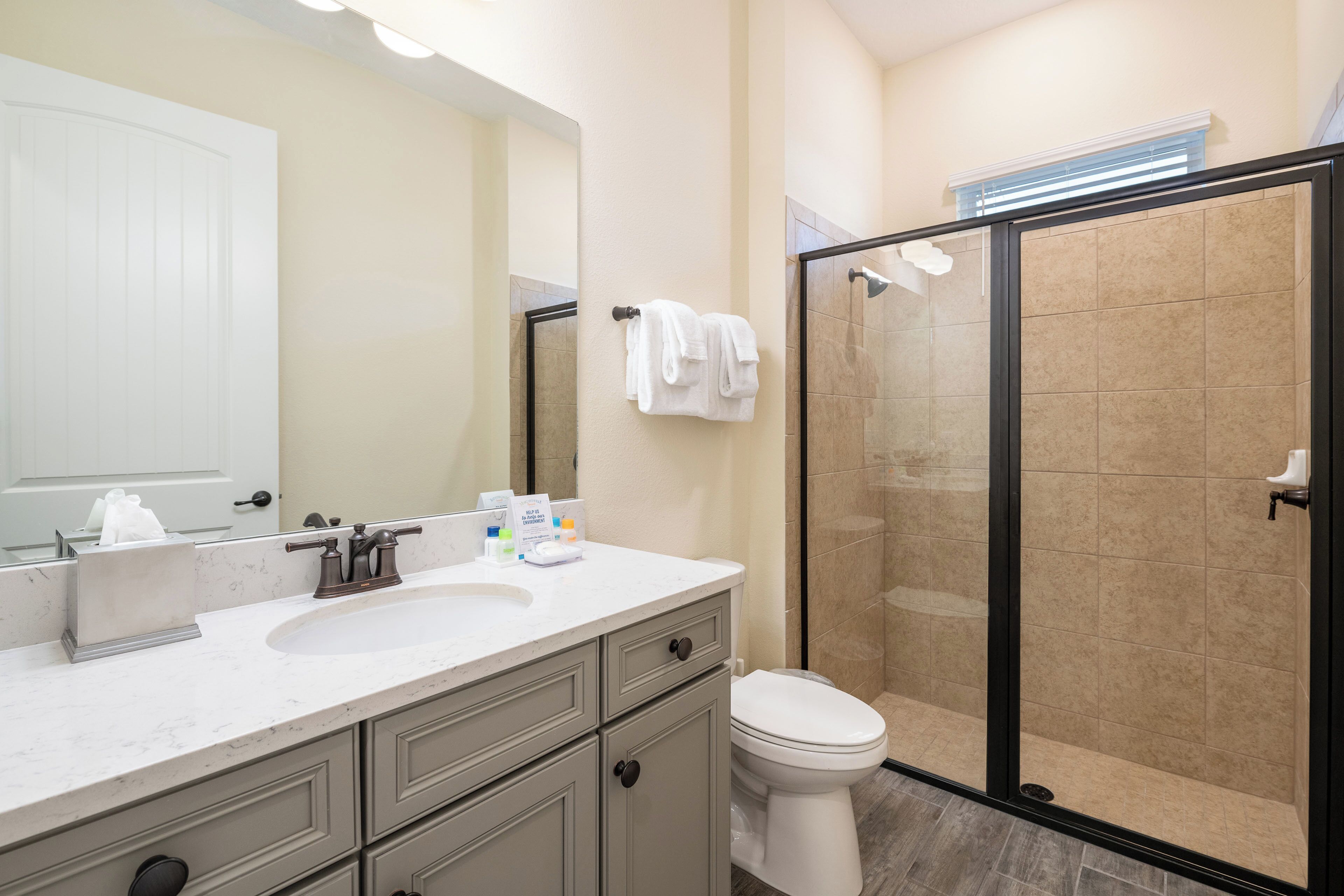 A modern bathroom with a white sink, a toilet, and a glass shower enclosure.