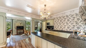 A spacious kitchen with a large island, wooden flooring, and a decorative chandelier.