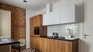 Una cocina compacta con pared de ladrillo decorativa, armarios de madera y salpicadero de azulejos.