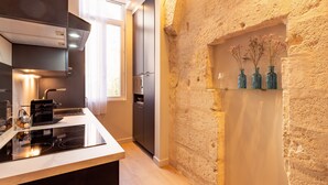 A modern kitchen with a built-in stove, dark cabinets, and a stone accent wall.