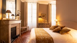 A hotel room with a large bed, a fireplace, and two bedside lamps.