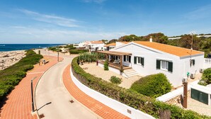 A coastal residential area with white houses, a curved road, and a beach in the background. - Mon Palau - House with sea view in Biniancolla (Biniancolla)