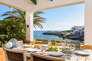 A table set for two with a view of the sea and a coastal town. - Sea Breeze-First line of the sea in Cala Torret (San Luis)